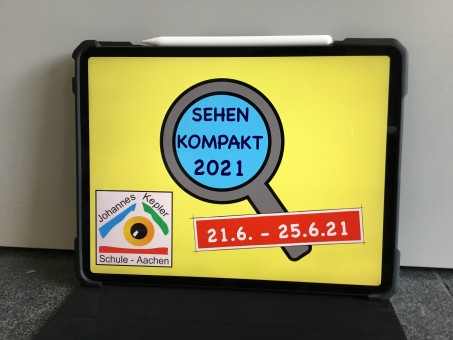 zeigt ein tablet mit der Darstellung einer Lupe und dem Textfeld "SEHEN KOMPAKT 2021". In der Ecke links unten das Logo der LVR-Johannes-Kepler-Schule. Hinweis auf das Datum der Veranstaltung vom 21.06.-25.06.2021