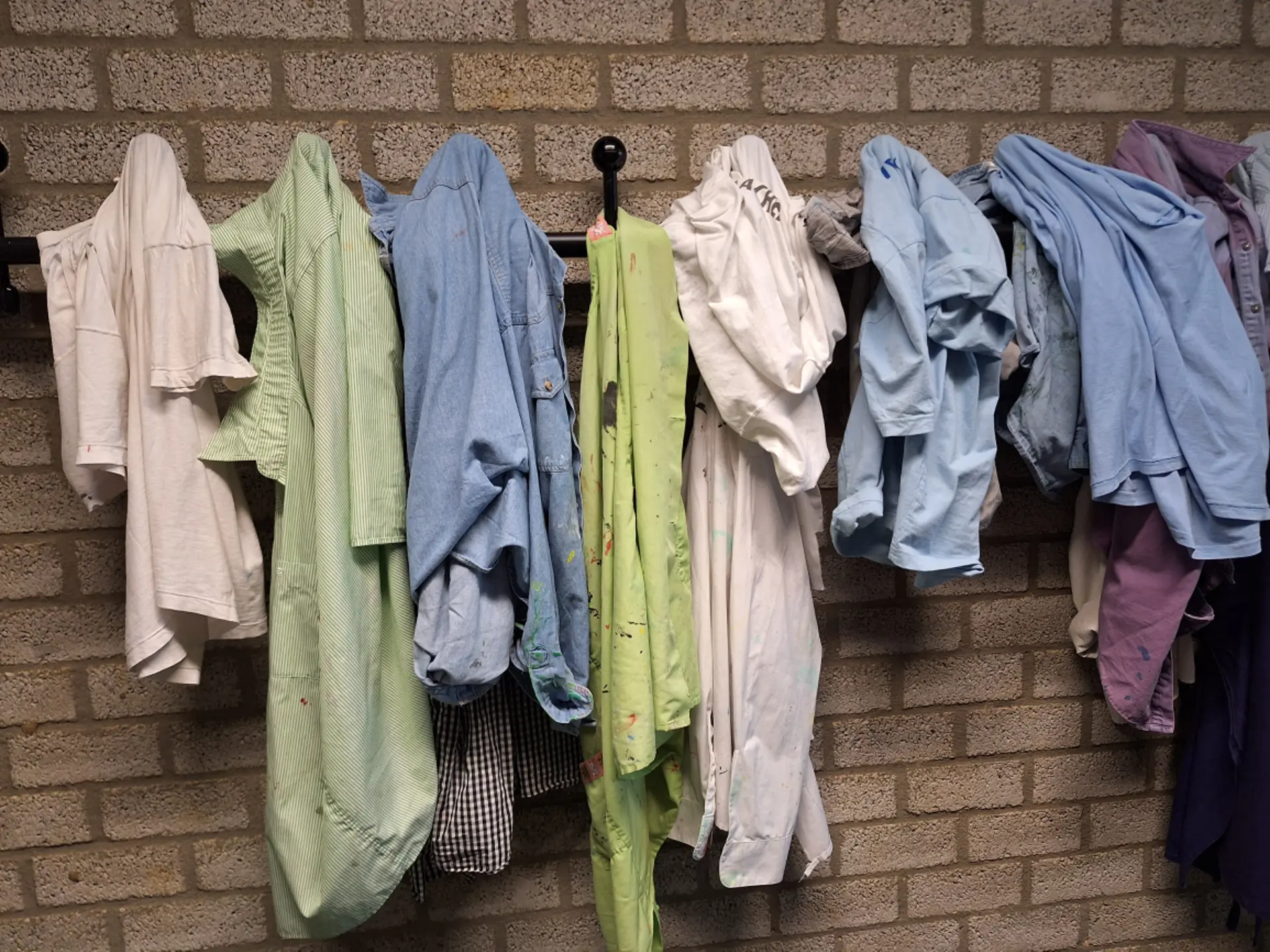 Malkittel hängen im Kunstraum an Haken