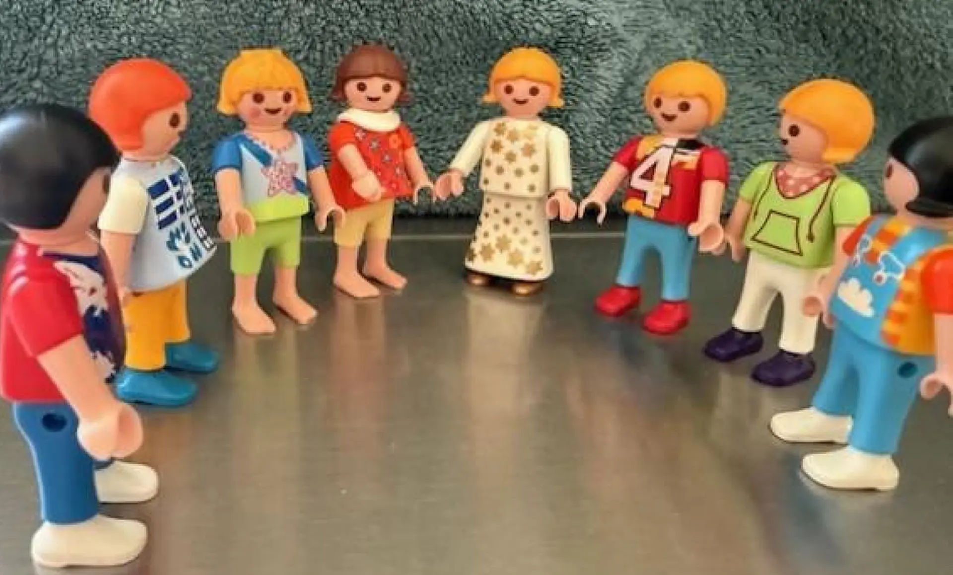 Eine Gruppe von verschiedenen Playmobil-Figuren steht aufgereiht im Kreis auf dem Tisch