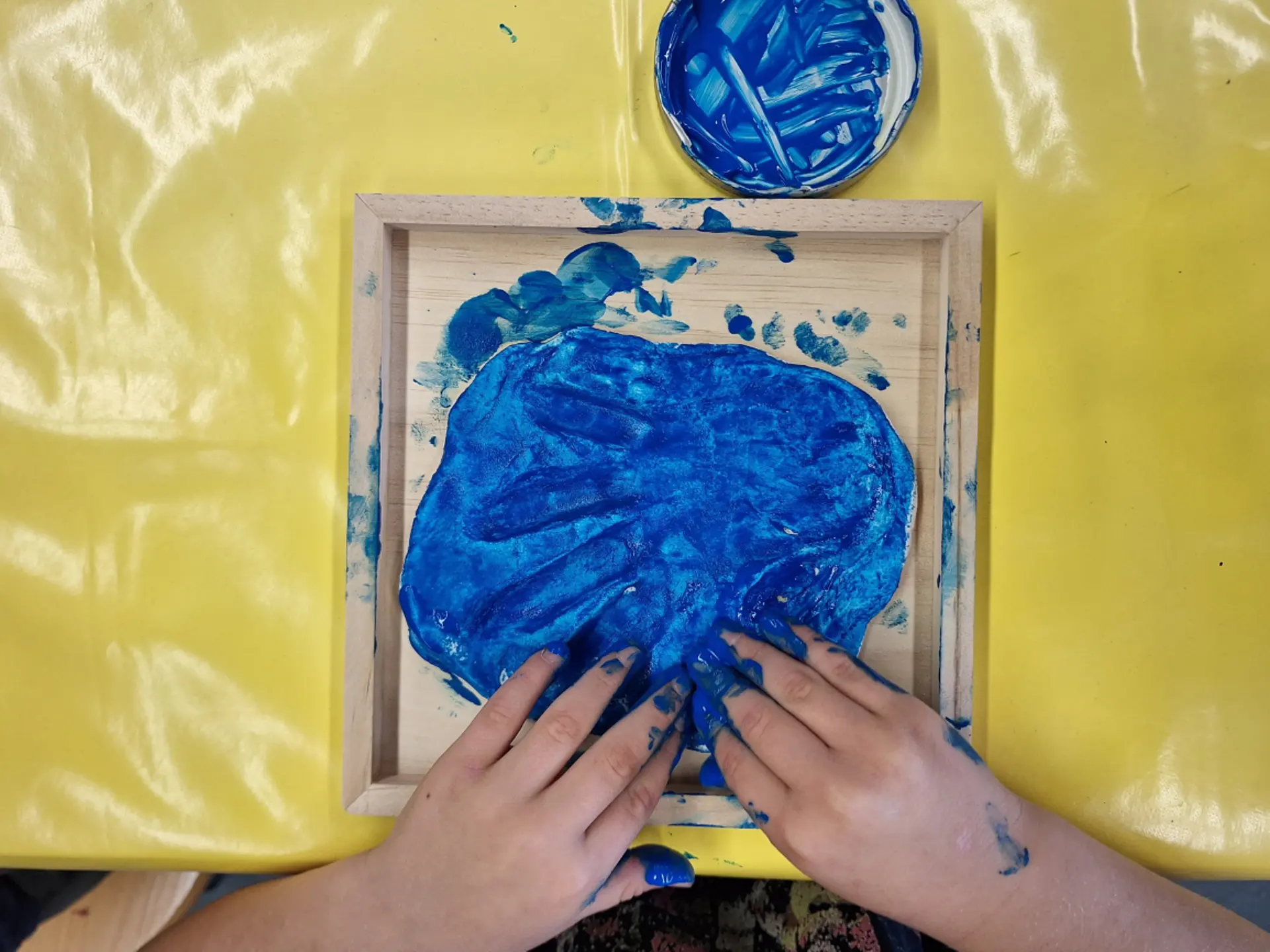 Kunstunterricht in der Primarstufe: Kind bemalt Gips-Handabdruck mit Farbe