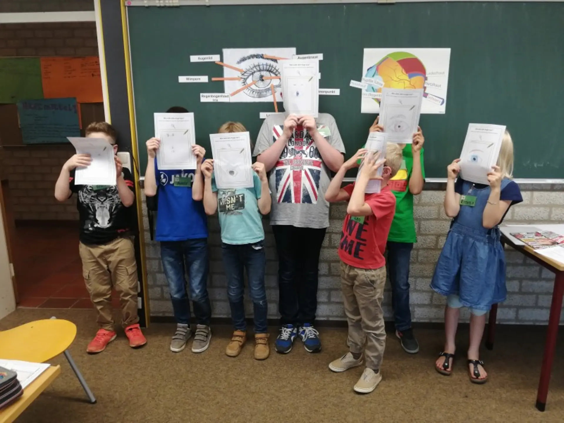 Kinder halten stolz ihre gemalten Bilder in die Luft