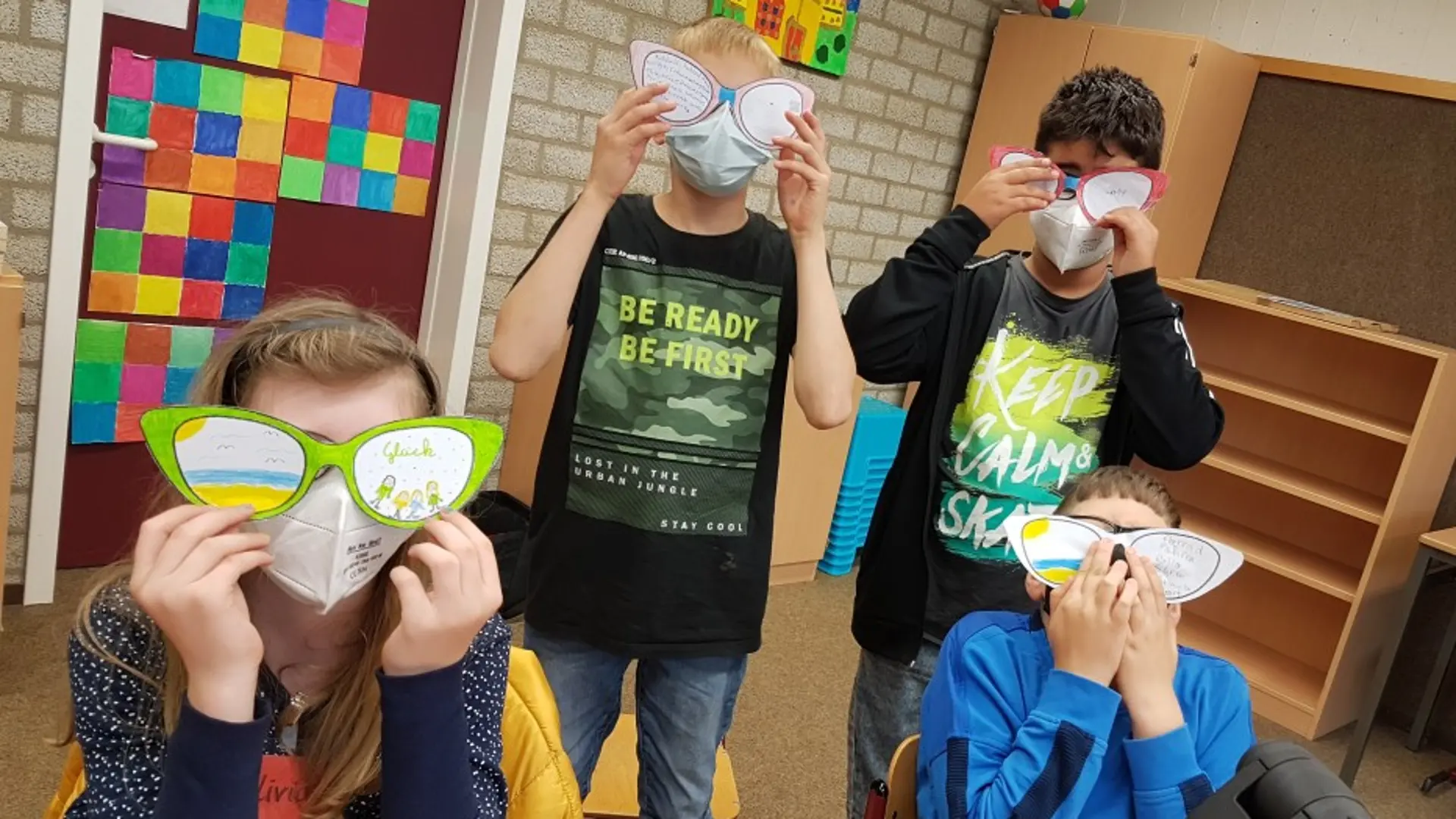 Kinder zeigen ihre gebastelten Brillen