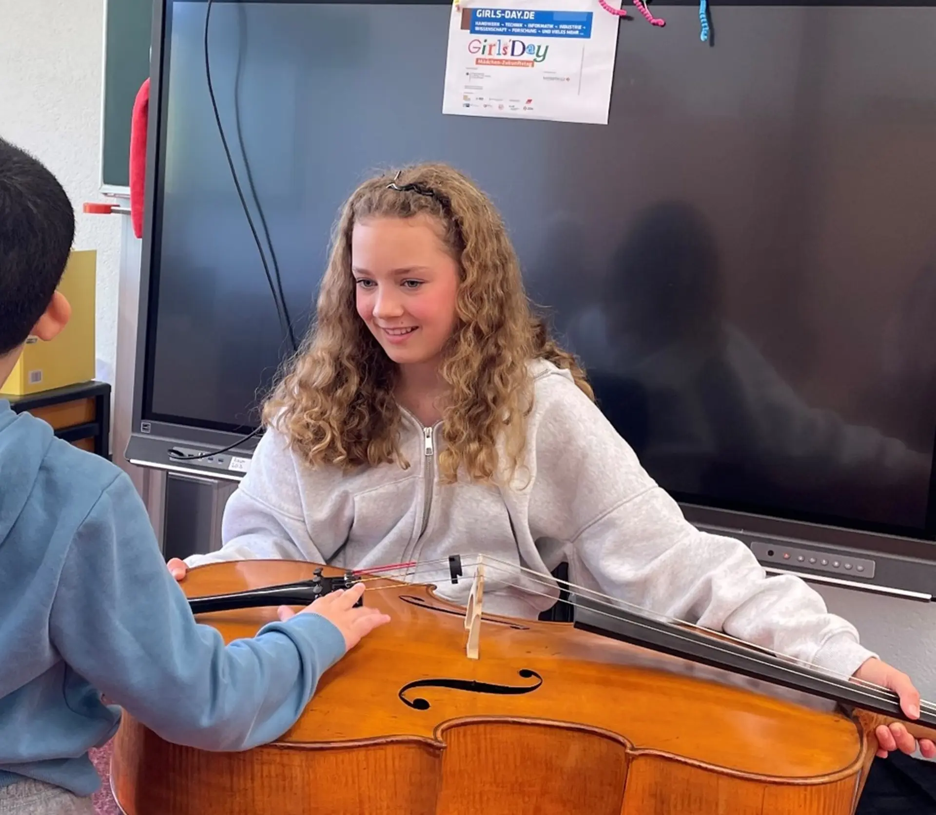 MÃ¤dchen mit Cello zeigt ihr Instrument einem Kind.