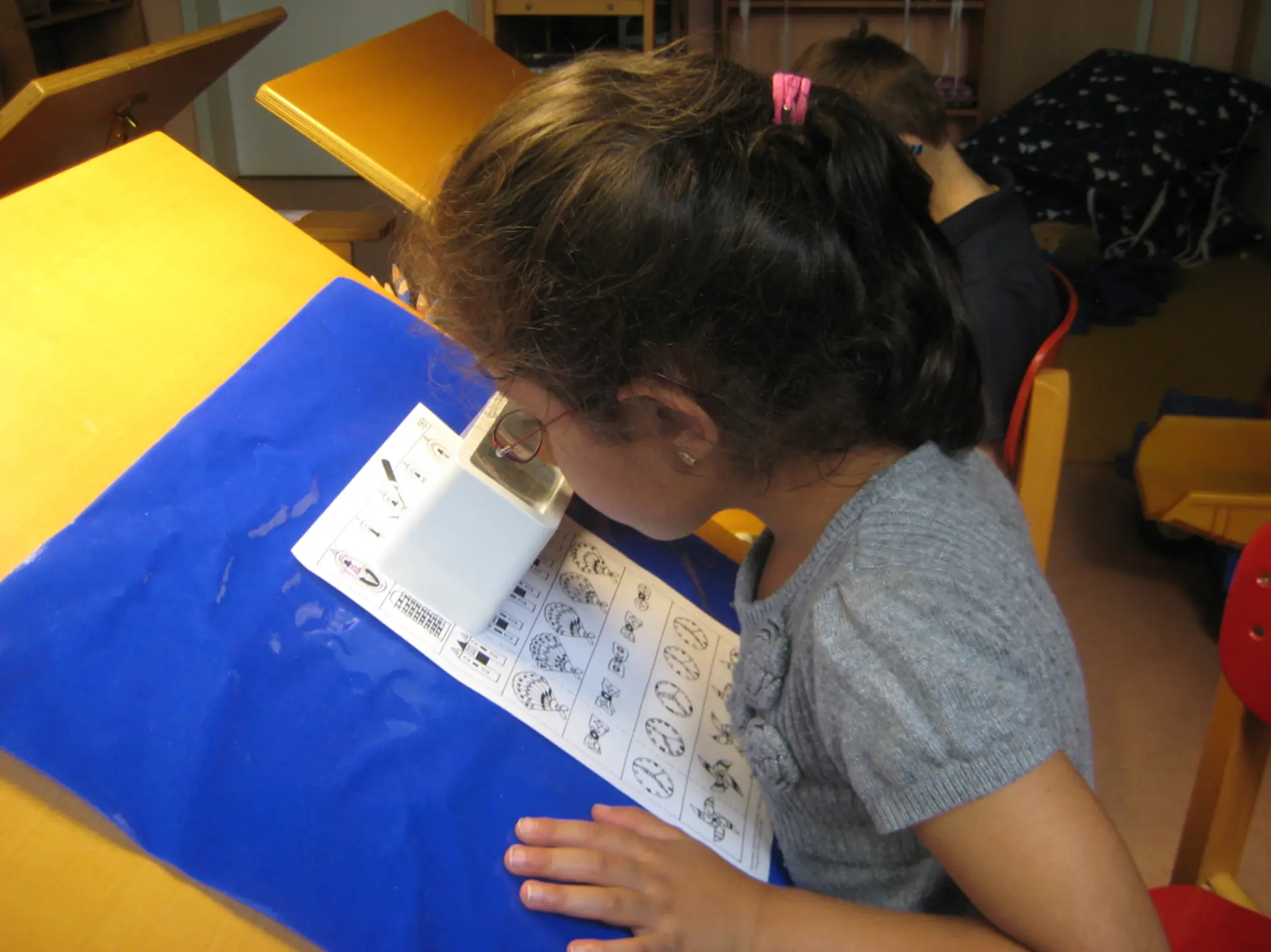 Kind arbeitet in der Vorschule mit einer Lupe